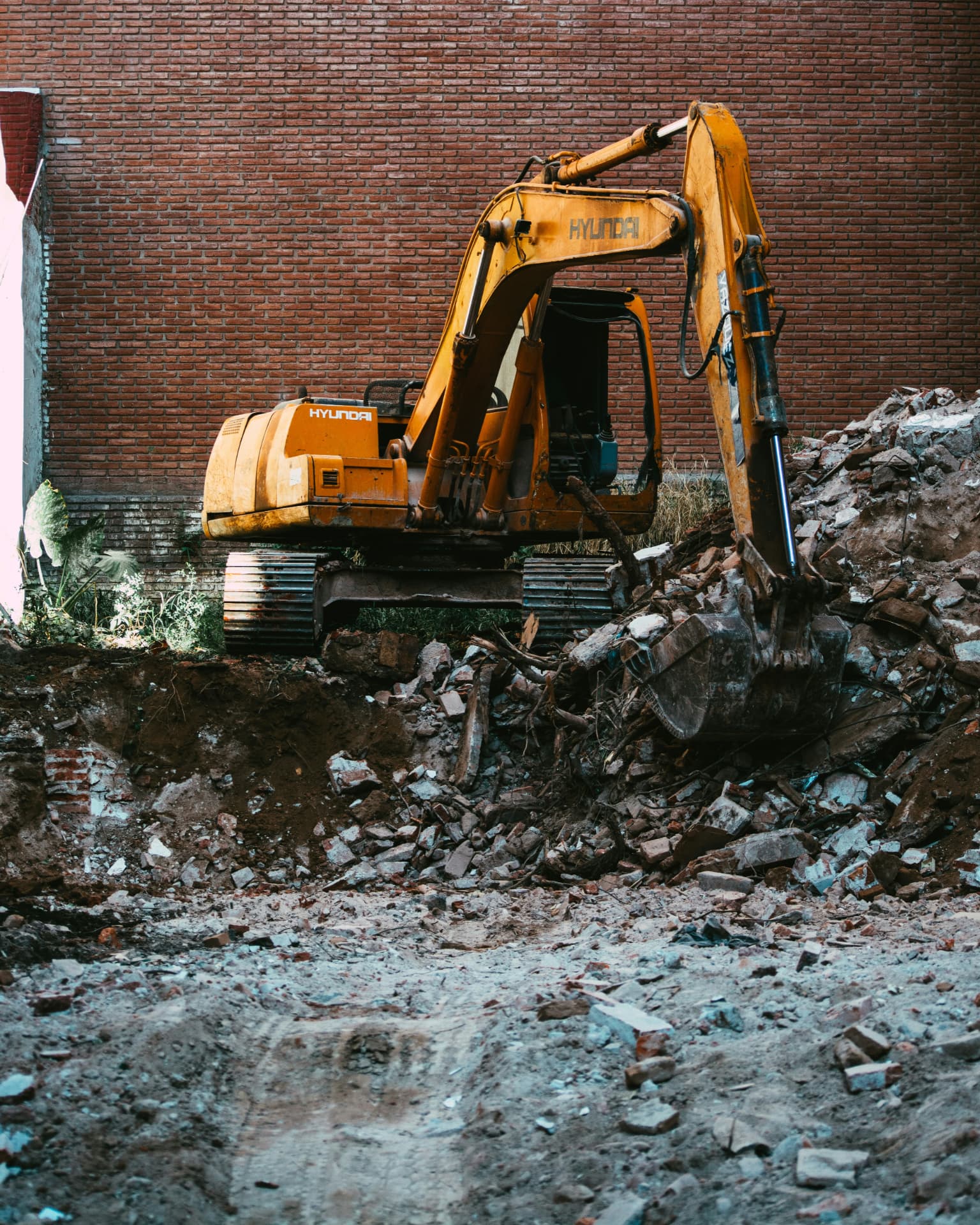 Yellow excavator demolishing a brick building